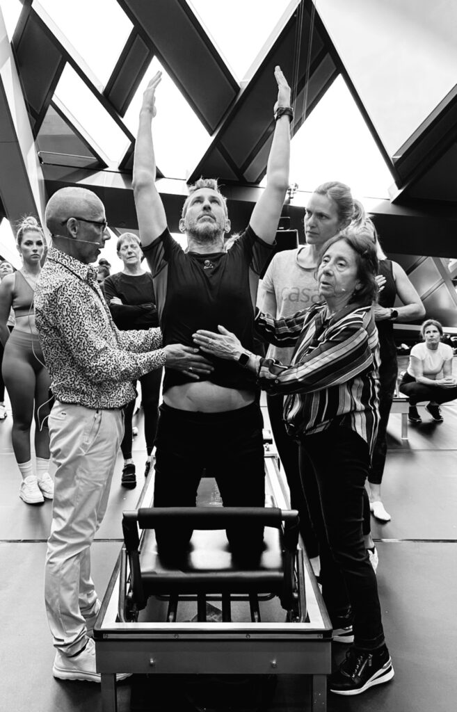 Carlos Castillo guiado por Sari Mejía y Javier Pérez Pont durante un ejercicio de Pilates en el Reformer, formación oficial de Romana’s Pilates Internacional.