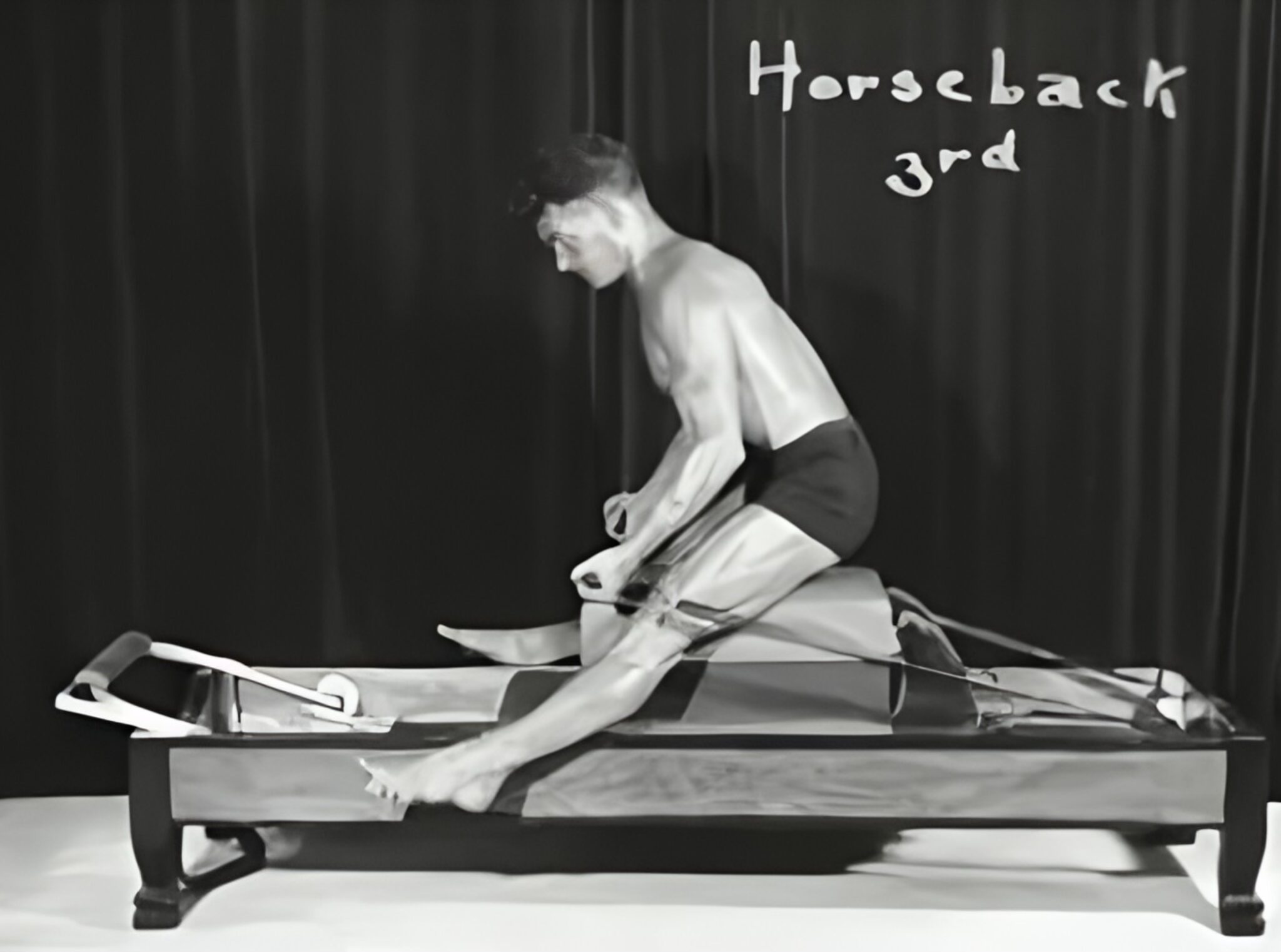 Joseph Pilates haciendo el reverse horback de la contrología creada por el. Joseph Pilates realizando el ejercicio Reverse Horseback, uno de los movimientos originales de la Contrología.