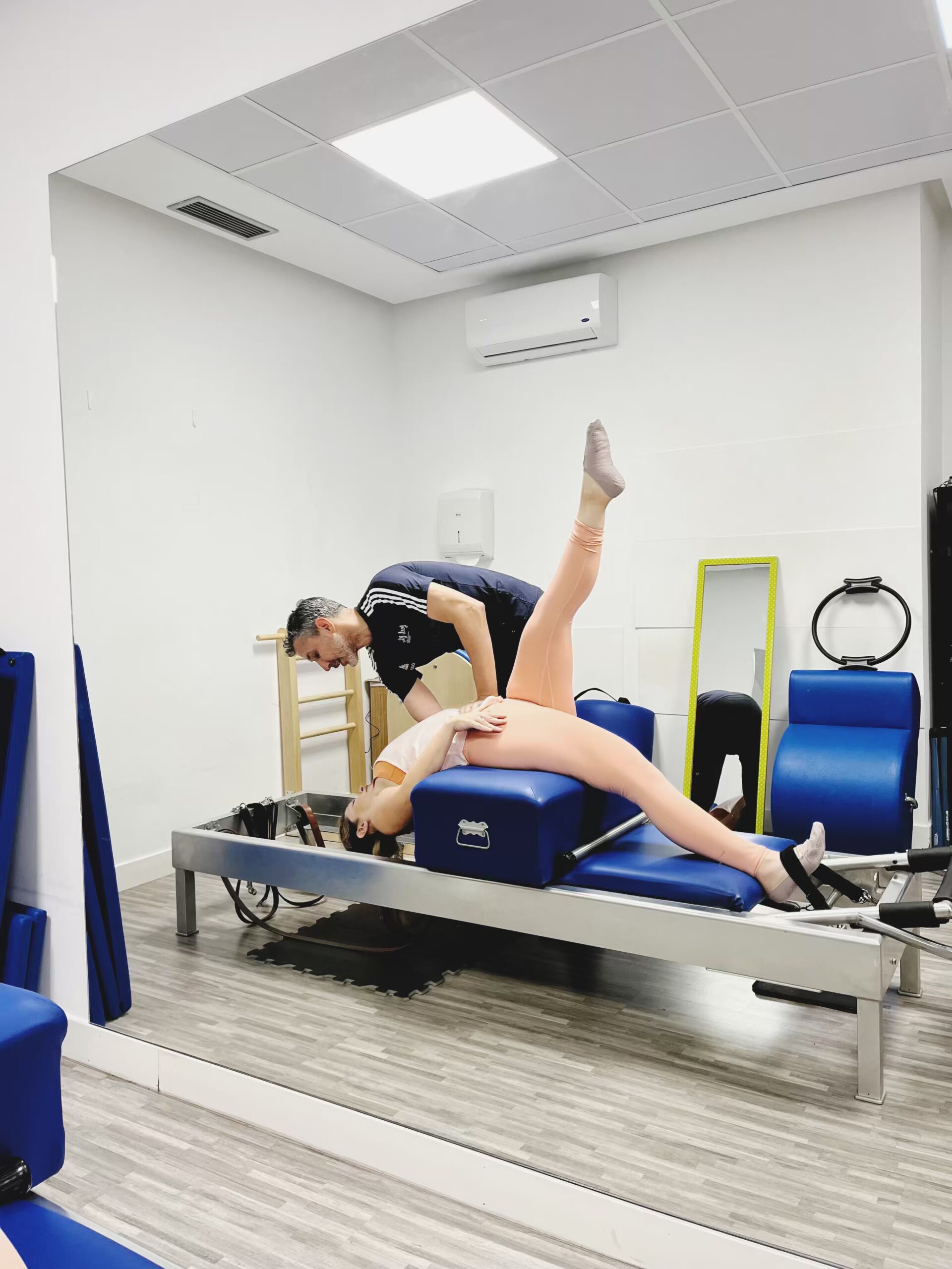 Pilates con aparatos en Feel Fit Pilates Madrid – Trabajo en Reformer original Pilates con aparatos. Alumna realizando ejercicios en Reformer bajo la supervisión de su profesor en Feel Fit Pilates Madrid, centro especializado en Romana’s Pilates.